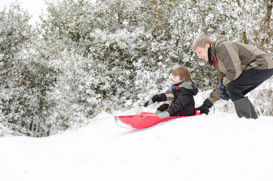 Dad helps son with sled on gentle slope