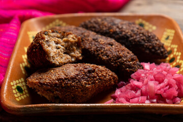 Mexican kibi with meat and onion on wooden background