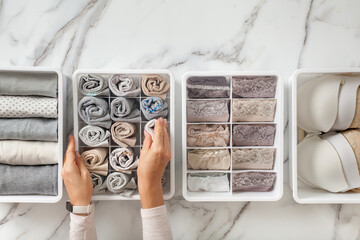 Woman hands placing organizer drawer divider with full of folded underwears and socks.