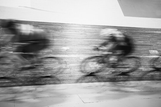 Blurry black and white image of track cyclists in pursuit during a race
