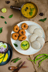 Top view of Idli, Wada, Sambar and Chutney. Traditional South Indian food, surrounded with lemon, raw mango and green chillies.