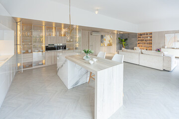 luxury interior design of modern trendy snow white kitchen in minimalistic style with island and two bar stools. huge windows to the floor and a glass rack for dishes