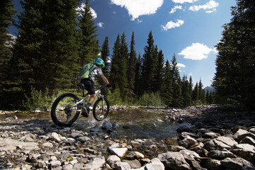A child rides a mountain bike through a cascade creek along the High Rockies Trail in Kananaskis...