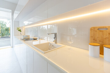 luxury interior design of modern trendy snow white kitchen in minimalistic style with island and two bar stools. huge windows to the floor and a glass rack for dishes
