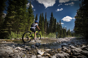 AC hildr rides their mountain bikes through a cascade creek along the High Rockies Trail in...