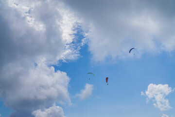 Paragliding in the cloudy blue sky.