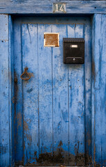 antique blue door faded by time, with a black mailbox and an ochre handle. Number 14