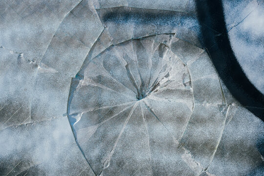 Spray painted graffiti on broken glass window of building exterior, close up