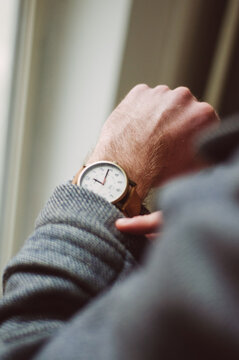 Young caucasian guy in coat looking at his watch