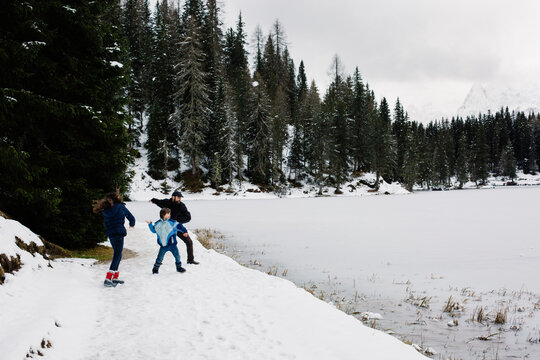 Family throwing snowballs and pieces of ice on a frozen lake to see which one goes farther