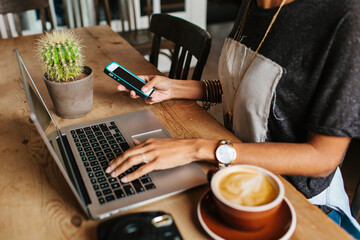 A woman eating brunch and working on her laptop and phone