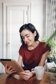 Brunette drinking a coffee using a digital tablet