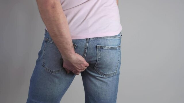 Man in jeans scratching his ass. Hemorrhoids, itching and burning in the anus