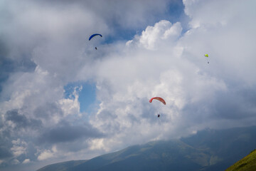 Fototapeta na wymiar Paragliding in the cloudy blue sky.