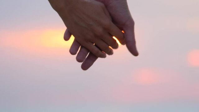 Close up of two lovers joining hands. Man and woman holding hands over the sunset blur background. Couple trust, Love and happiness concept. Romantic relationships. Sky background Cinematic scene