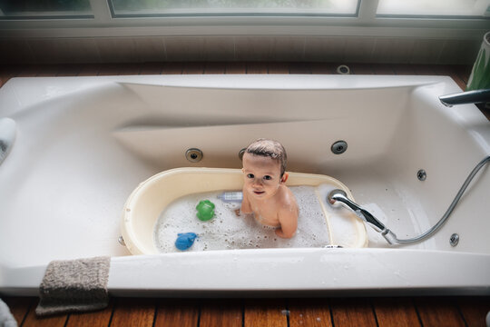 Baby boy taking a bath in a big bathtub