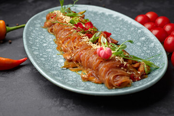 Boiled rice noodles with vegetables, sesame seeds, green onions, cherry tomatoes and hot red pepper on a plate
