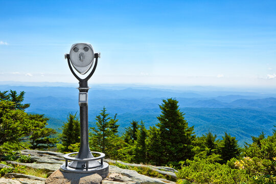 Coin operated telescope stands before a hazy blue ridge mountain