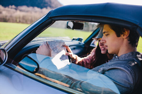 Young couple looking at the road map in the car