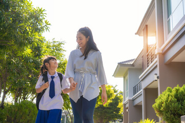 Happy Asian mother and daughter primary school student walking to school in the morning school routine for day in the life getting ready for school.