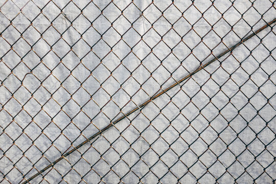 Chainlink fence in front of silver tarp