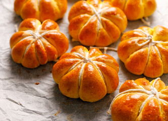 Pumpkin shaped dinner rolls on baking paper close up view