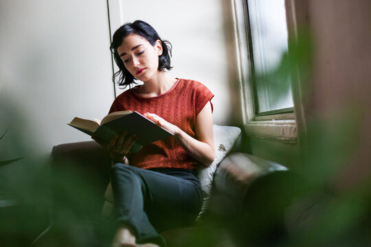 Brunette reading a book on the sofa