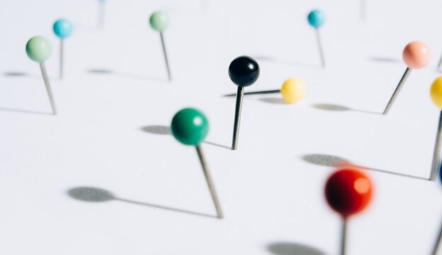 A bunch of push pins in a white foam board.