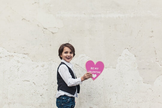 Smiling little boy holding a pink Valentine heart
