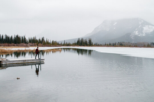 Young woman walking on dock in lake during winter