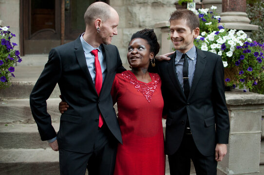 newlywed grooms converse with their wedding officiant