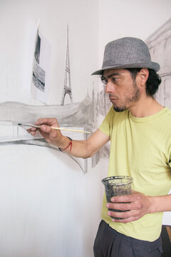 Artist doing a mural painting with scenes from Paris