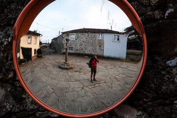 Photographer shooting a self portrait in a road cross mirror, Spain