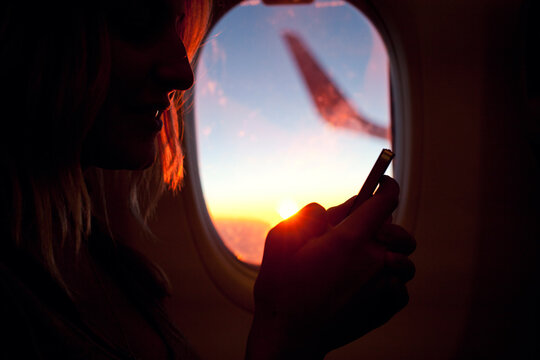Young woman sitting in an airplane using her phone