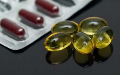 Medical capsules yellow fish oil on a black background.