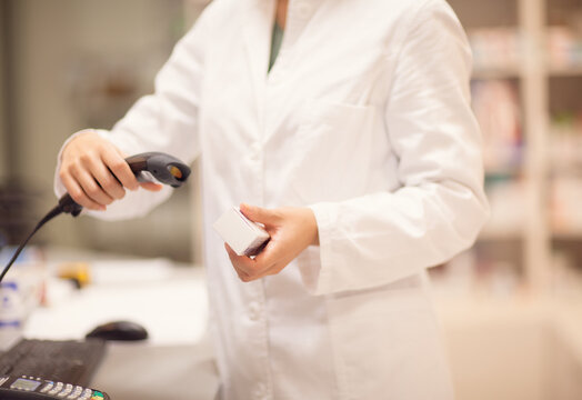 Pharmacist scanning a box of medicines at the counter.