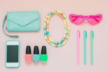 Overhead shot of brightly colored feminine objects on a pink background