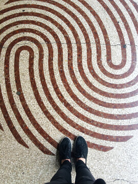 Woman feet standing on a abstract swirl mosaic tiles