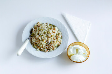 Traditional Turkish rice pilaf with peas and noodles on white with yogurt and compote