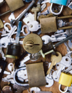Key in a lock with various keys and padlocks in the background