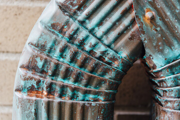 Corroded copper downspout on the side of a wall