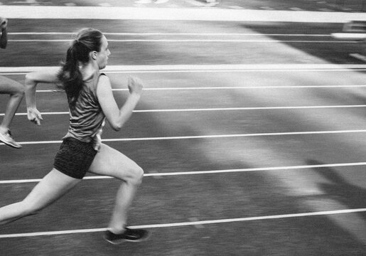 Teenage girl running toward the finish line and in first place at a track meet