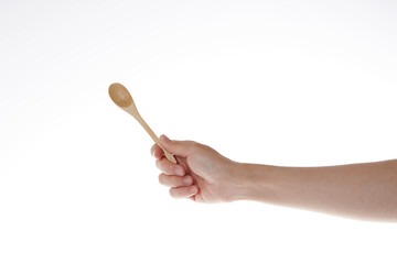hand holding teaspoon made of wood.