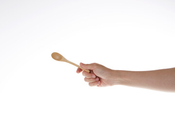 hand holding teaspoon made of wood.