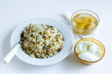 Traditional Turkish rice pilaf with peas and noodles on white with yogurt and compote
