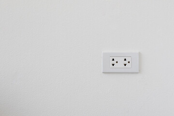 White electrical plug on the white wall.