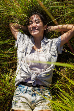A young asian woman is lying in the gras