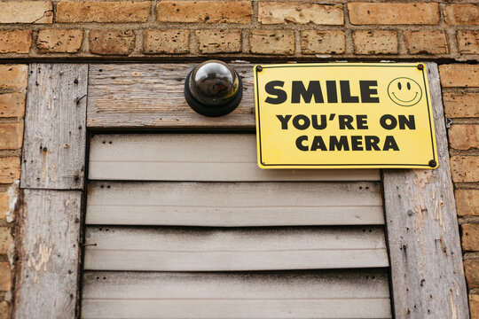 Surveillance camera on an outside wall with a sign on it