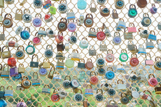 Display of colorful locks on a chain link fence.