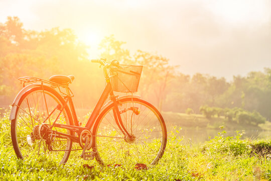 Smooth and beautiful scenery with a bike as the sun rises over the horizon. Vintage style light effect The gentle focus of the bicycle parked in the meadow by the pond. Retro concept.